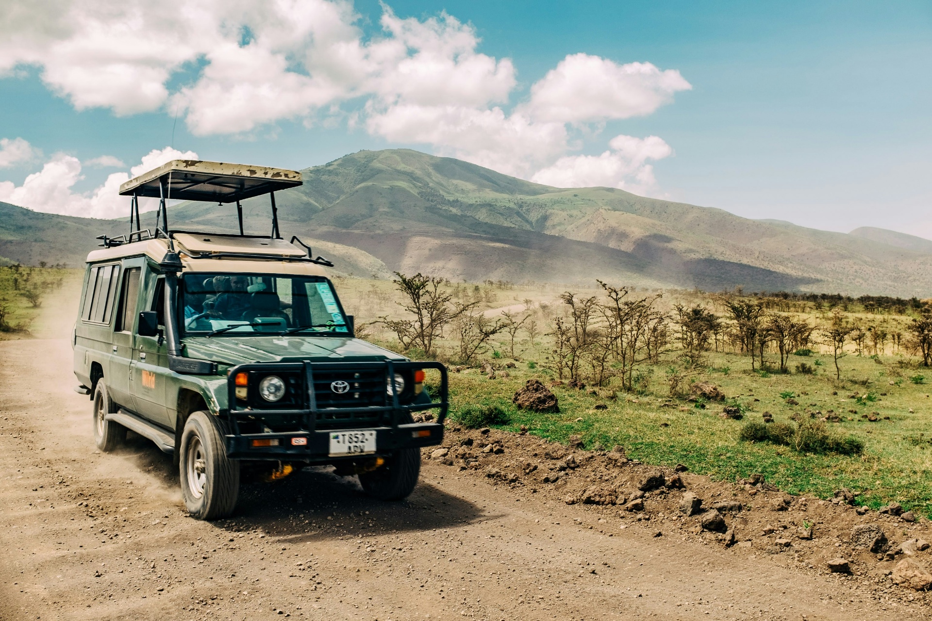 Safari jeep on a dirt road with mountains in Kenya